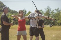 Allenatore istruire donna circa tiro con l'arco al campo di addestramento — Foto stock