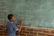 Школярка пише на дошці в класі в школі — стокове фото