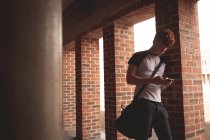 Студент коледжу за допомогою мобільного телефону в коридорі — стокове фото