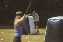 Hombre y mujer practicando tiro con arco en el campamento de entrenamiento en un día soleado - foto de stock