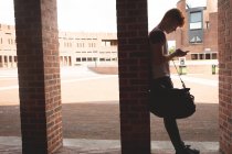 Студент коледжу за допомогою мобільного телефону в коридорі — стокове фото