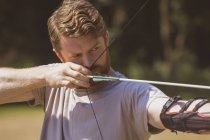 Человек практикующий стрельбу из лука в учебном лагере в солнечный день — стоковое фото