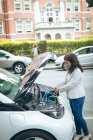 Vue latérale de la femme d'affaires recharge voiture électrique à la station de charge — Photo de stock