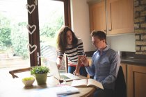 Couple discuter sur ordinateur portable dans la cuisine à la maison — Photo de stock