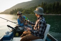 Два рибалки мають пиво під час риболовлі в річці в сільській місцевості — стокове фото
