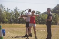 Treinador instruindo mulher sobre tiro com arco no acampamento de inicialização — Fotografia de Stock