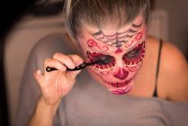 Woman applying mascara on eyes for halloween celebration — Stock Photo