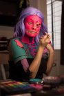 Mujer pintando su cara con pincel para la celebración de Halloween - foto de stock
