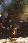 Вмістити чоловіка, що запалює вогонь у таборі для завантаження — стокове фото