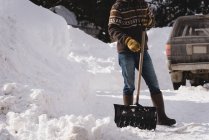 Hombre limpiando nieve con pala de nieve durante el invierno - foto de stock