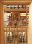 Vista lateral do estudante universitário lendo um livro na biblioteca — Fotografia de Stock