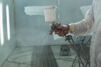 Mecânico masculino usando tinta spray na garagem — Fotografia de Stock