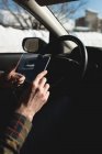 Человек, использующий стеклянный цифровой планшет в автомобиле зимой — стоковое фото