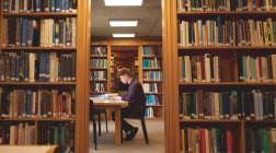 Vista laterale dello studente universitario utilizzando laptop in biblioteca — Foto stock
