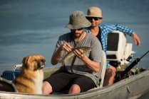 Pescador segurando um peixe no barco no campo — Fotografia de Stock