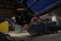 Mécanicien masculin entretenant une voiture dans le garage — Photo de stock
