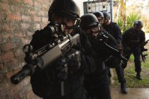 Военнослужащие с винтовкой, идущие к стене во время военной подготовки — стоковое фото