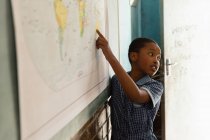 Schoolboy explicando sobre mapa do mundo em sala de aula na escola — Fotografia de Stock