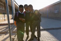 Schüler nutzen an einem sonnigen Tag das Handy auf dem Schulcampus — Stockfoto