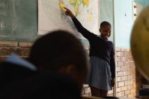 Школярка пояснює світову карту в класі в школі — стокове фото
