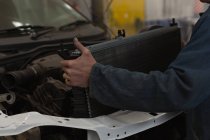Mecânico masculino colocando radiador de carro no capô na garagem — Fotografia de Stock