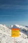 Sinal de aviso em montanhas nevadas durante o inverno — Fotografia de Stock