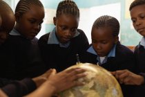 Schoolkids using globe in classroom at school — Stock Photo