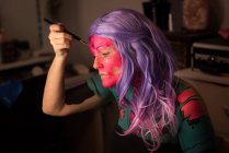 Женщина красит лицо кисточкой для празднования Хэллоуина — стоковое фото