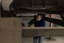 Meccanico con tablet digitale durante la manutenzione di un'auto in garage — Foto stock
