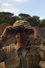 Soldat militaire regardant à travers les jumelles pendant l'entraînement militaire — Photo de stock
