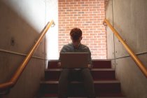Estudante universitário usando laptop em escadas no campus — Fotografia de Stock