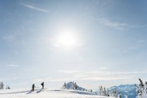 Лыжники, идущие по снежной горе зимой — стоковое фото