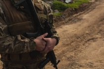 Середня частина військовослужбовця, що стоїть з гвинтівкою під час військової підготовки — стокове фото