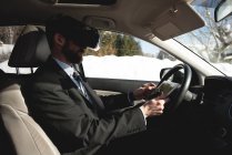 Uomo d'affari che utilizza cuffie realtà virtuale con tablet digitale in auto — Foto stock