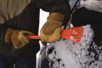 Середня частина людини очищає сніг від автомобільного лобового скла взимку — стокове фото