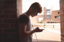 Estudante universitário usando telefone celular no corredor — Fotografia de Stock