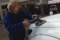 Aufmerksame Mechanikerin poliert Auto in Garage — Stockfoto