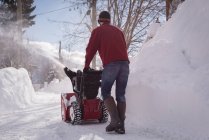 Rückansicht eines Mannes mit Schneefräse in verschneiter Region — Stockfoto