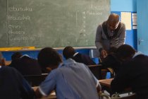 Professora do sexo masculino ensinando alunos na turma na escola — Fotografia de Stock