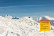 Panneau d'avertissement sur une montagne enneigée pendant l'hiver — Photo de stock