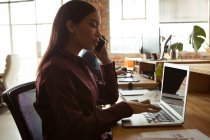 Führungskraft benutzt Laptop beim Telefonieren im Büro — Stockfoto