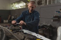 Mecánico masculino servicio de un coche en el garaje - foto de stock