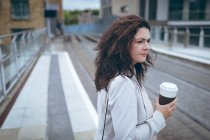 Молода бізнес-леді з чашкою кави стоїть на залізничній станції — стокове фото