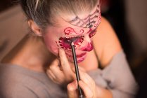 Femme peignant son visage avec un pinceau pour la célébration d'Halloween — Photo de stock