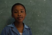 Schoolgirl standing near chalkboard in classroom at school — Stock Photo