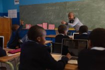 Учитель-мужчина, обучающий учеников в классе в школе — стоковое фото