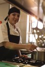 Chef fêmea degustação de alimentos na cozinha no restaurante — Fotografia de Stock