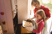 Mother and daughter looking at the baked cookies in the kitchen — Stock Photo