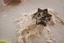 Close-up de estrela em forma de cortador de biscoito na farinha — Fotografia de Stock