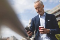 Low angle view of businessman using mobile phone at promenade — Stock Photo